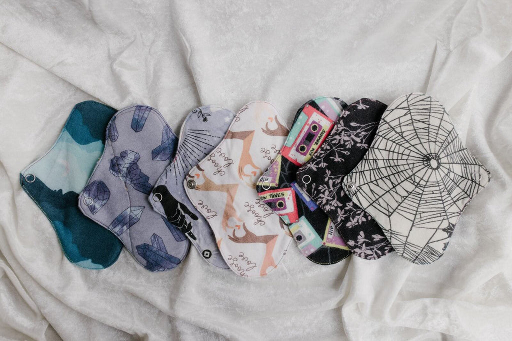 Tween Organic Pads Light Flow in various designs and colors displayed on a soft fabric background.